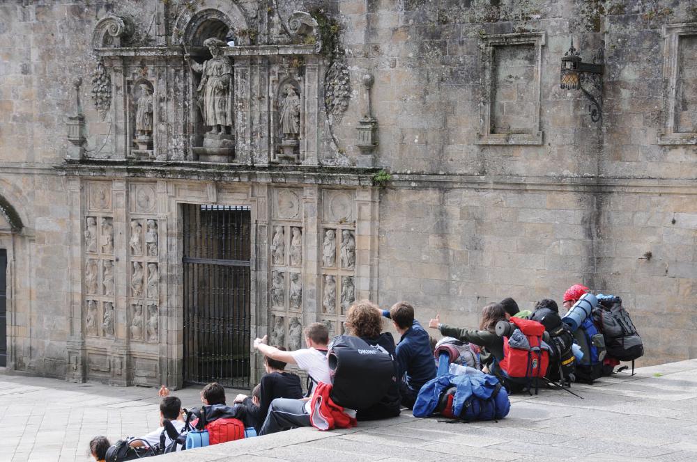 Pilgergruppe sitzt auf Treppenstufen neben Kirche